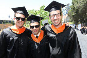 three students posing in graduation caps