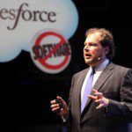 Marc Benioff speaking on stage in front of a SalesForce sign