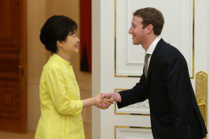 Mark Zuckerberg smiling and shaking hands with a woman