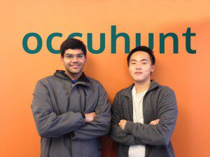 two students posing in front of an Occuhunt sign