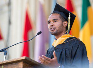 a student in a grad cap speaking at a podium