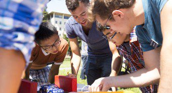 five students reading instructions on a table