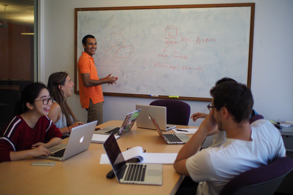 a group of students laughing with laptops