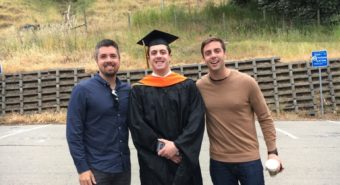 Male graduate student with two other men in parking lot