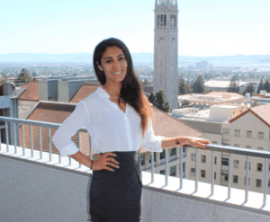 Tara poses by a railing; in the background is Berkeley campus and the campanile.