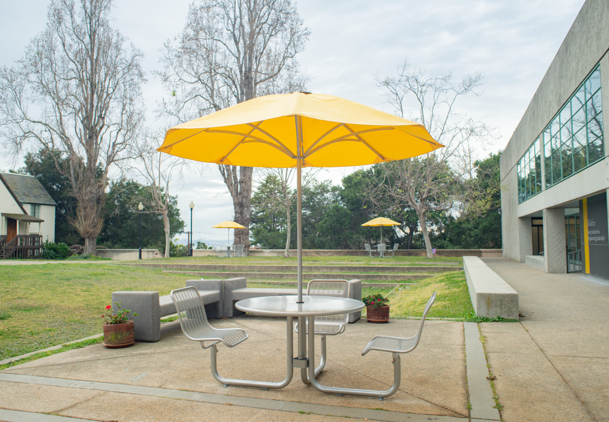 A table with an umbrella and seating outside Mudd Hall.